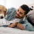 man smiles and pets his dog on a bed